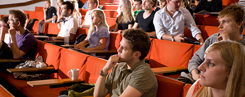 Students at a lecture in an auditorium with orange seats