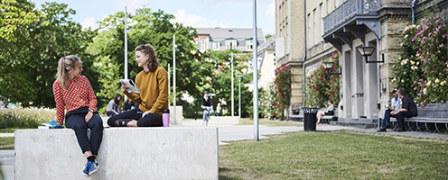 Two female students sitting outside some of the buildings on Frederiksberg Campus